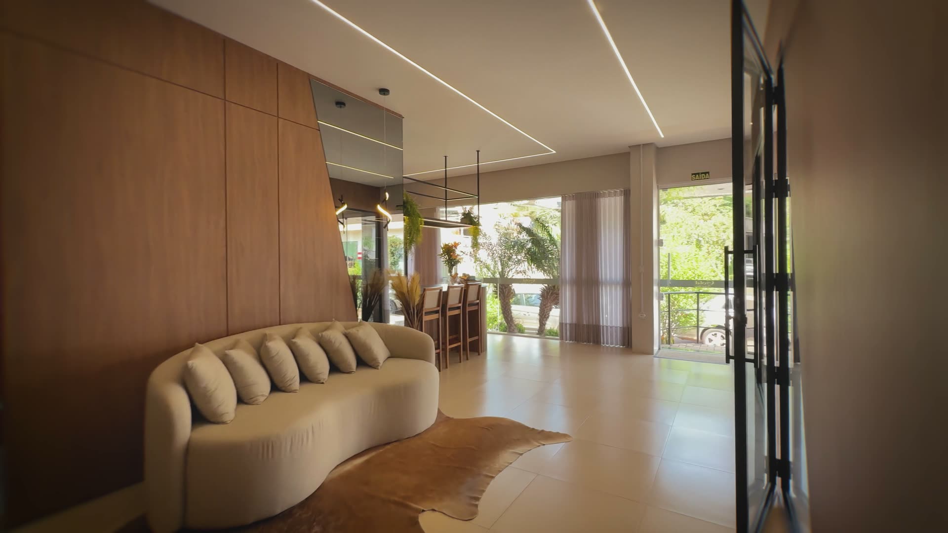 Entrada do showroom da Gold Möbel Haus, em Mato Leitão: sofá curvo contra a parede de madeira e as portas de vidro ao fundo.